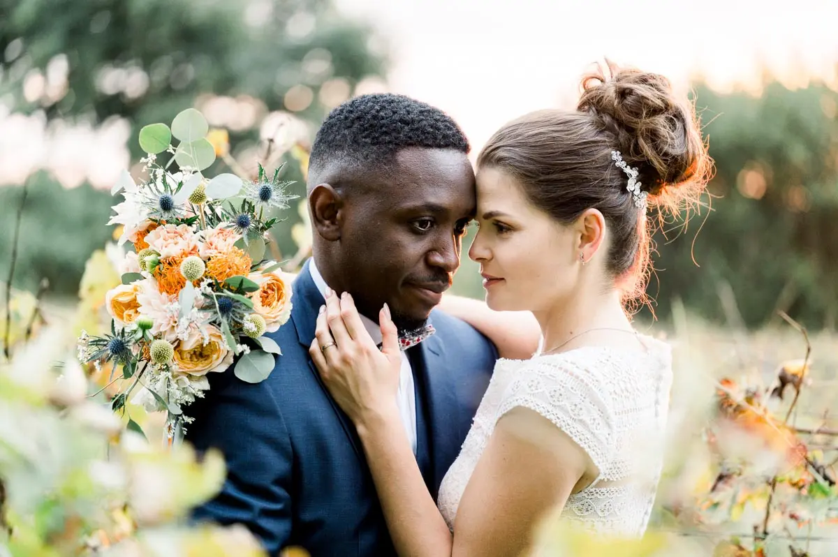 Bride and groom forehead to forehead with a colourful bouquet, Château Courtade-Dubuc