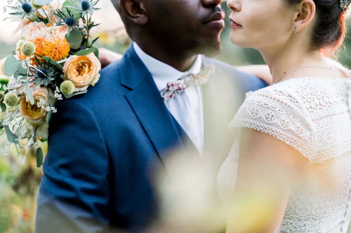 Close-up of the couple almost nose to nose, orange bouquet in the foreground