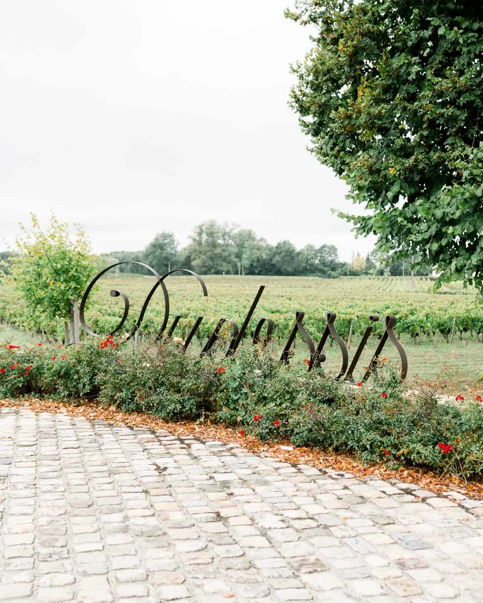 Wrought-iron Duplessis lettering above a rose bed in front of the vines