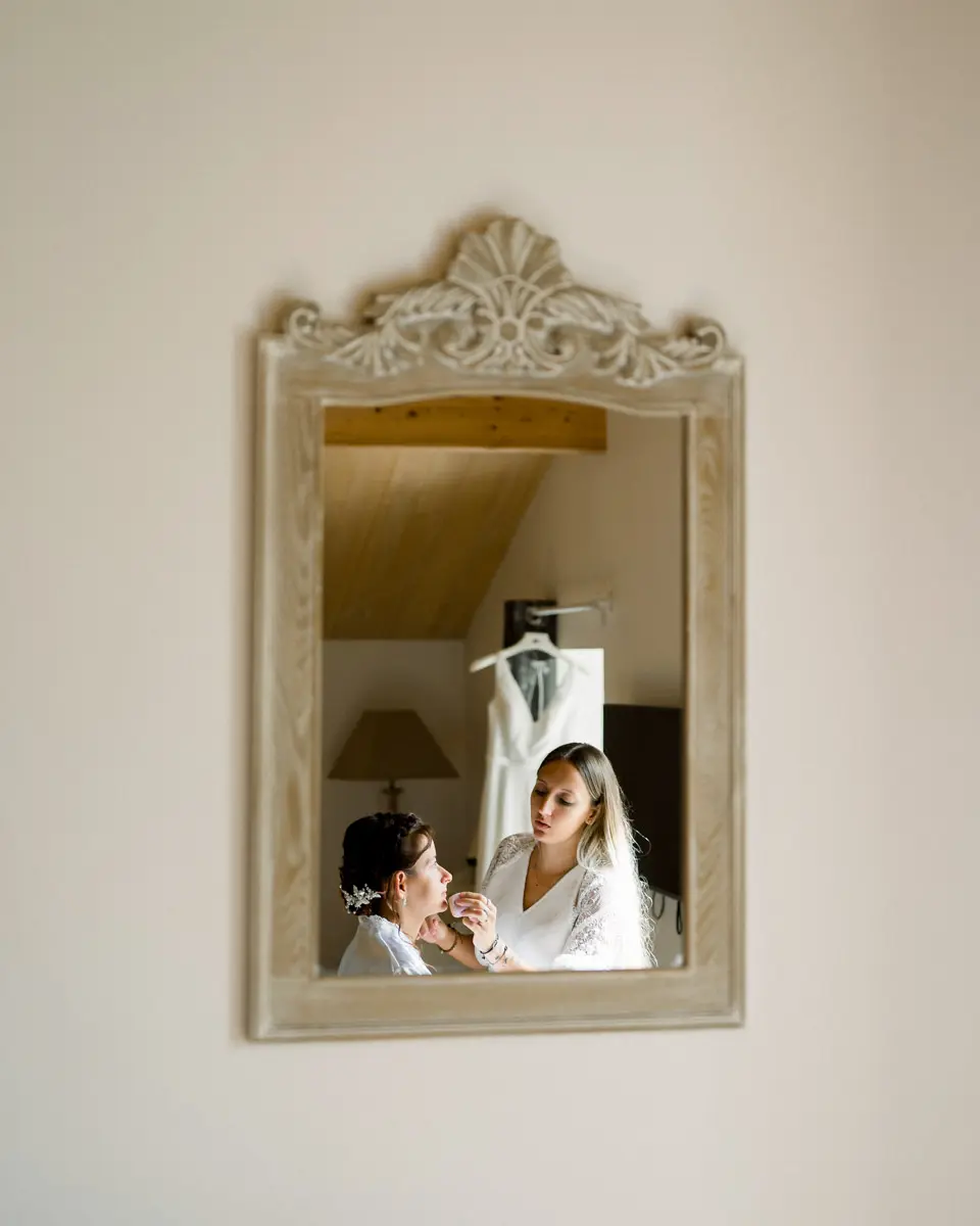 Bride's makeup session reflected in a carved vintage mirror