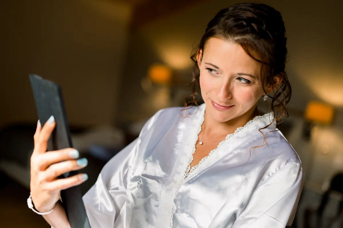 Laetitia in a satin robe looking into a hand mirror