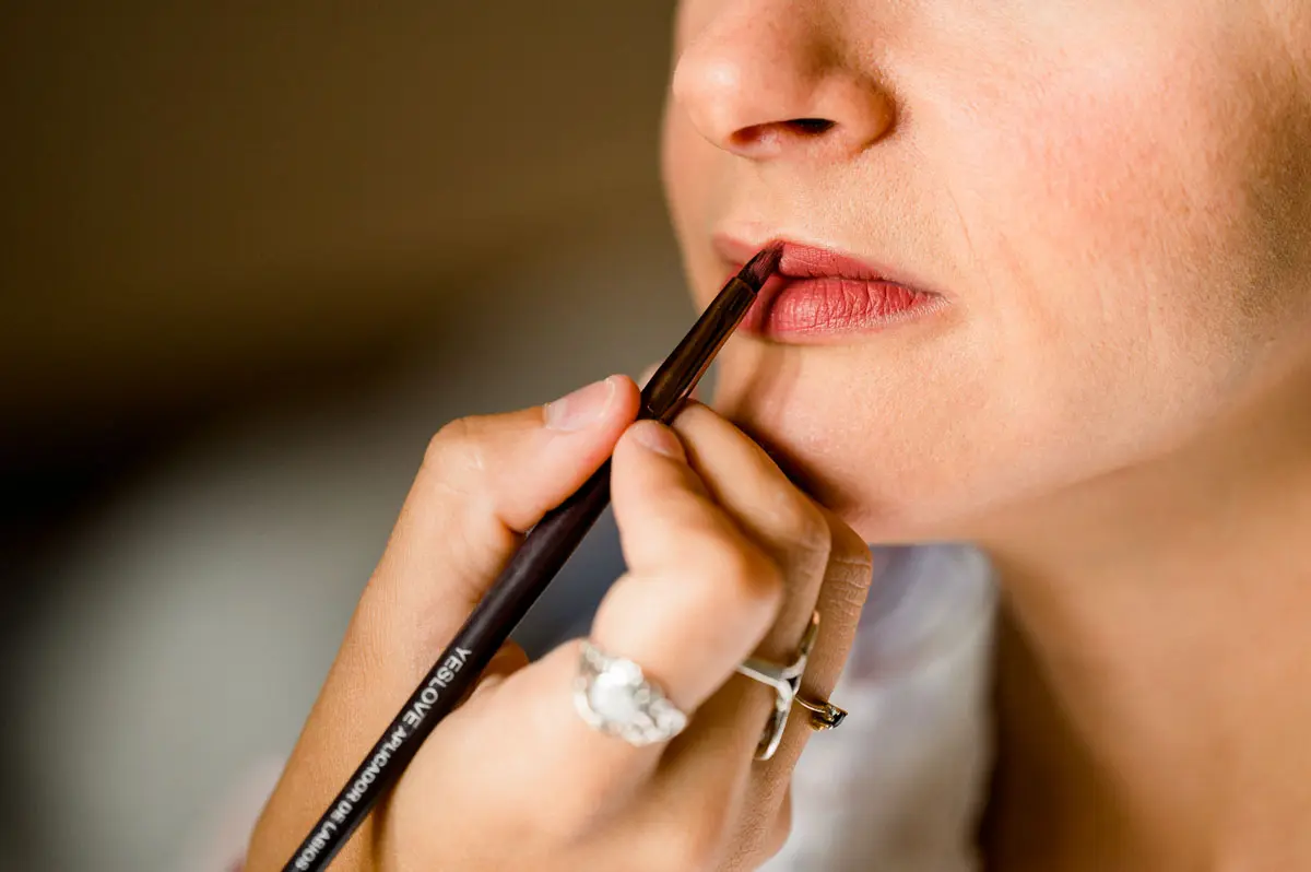 Close-up of lipstick being applied to the bride with a brush