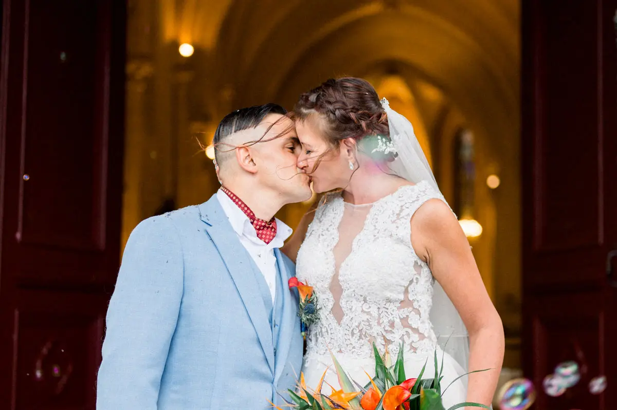 Newlyweds kissing at the church door under the bubbles