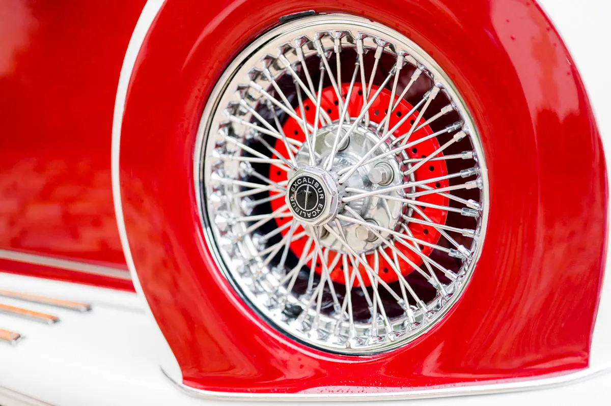 Chrome spoked wheel on the red wing of a classic car