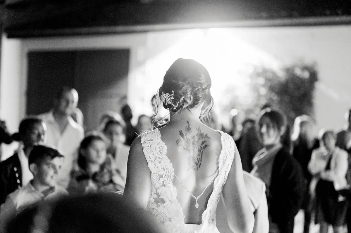 Bride seen from behind facing her guests during the party, in black and white
