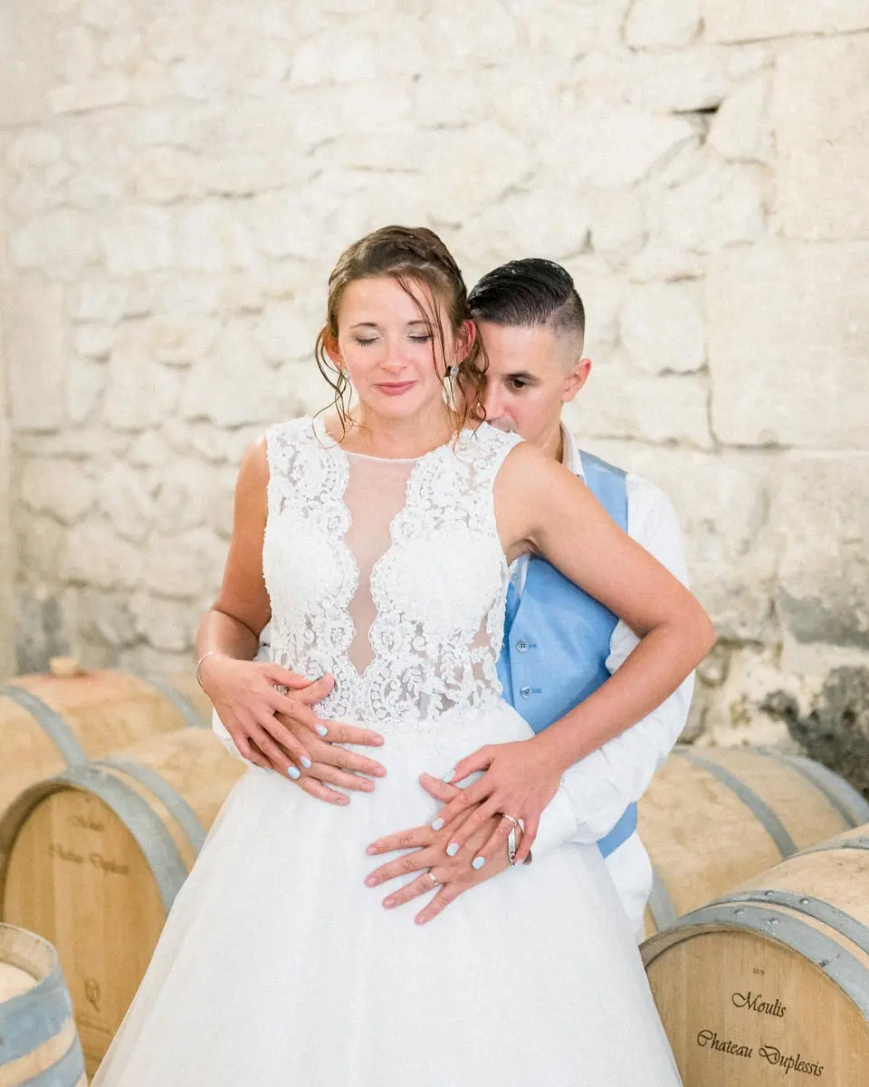 Couple embracing in front of the barrels in the Château Duplessis cellar in the Médoc