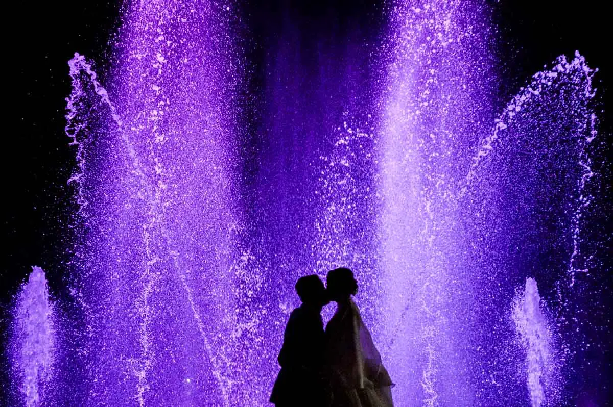Silhouette of the couple kissing before the purple jets of the fountain show