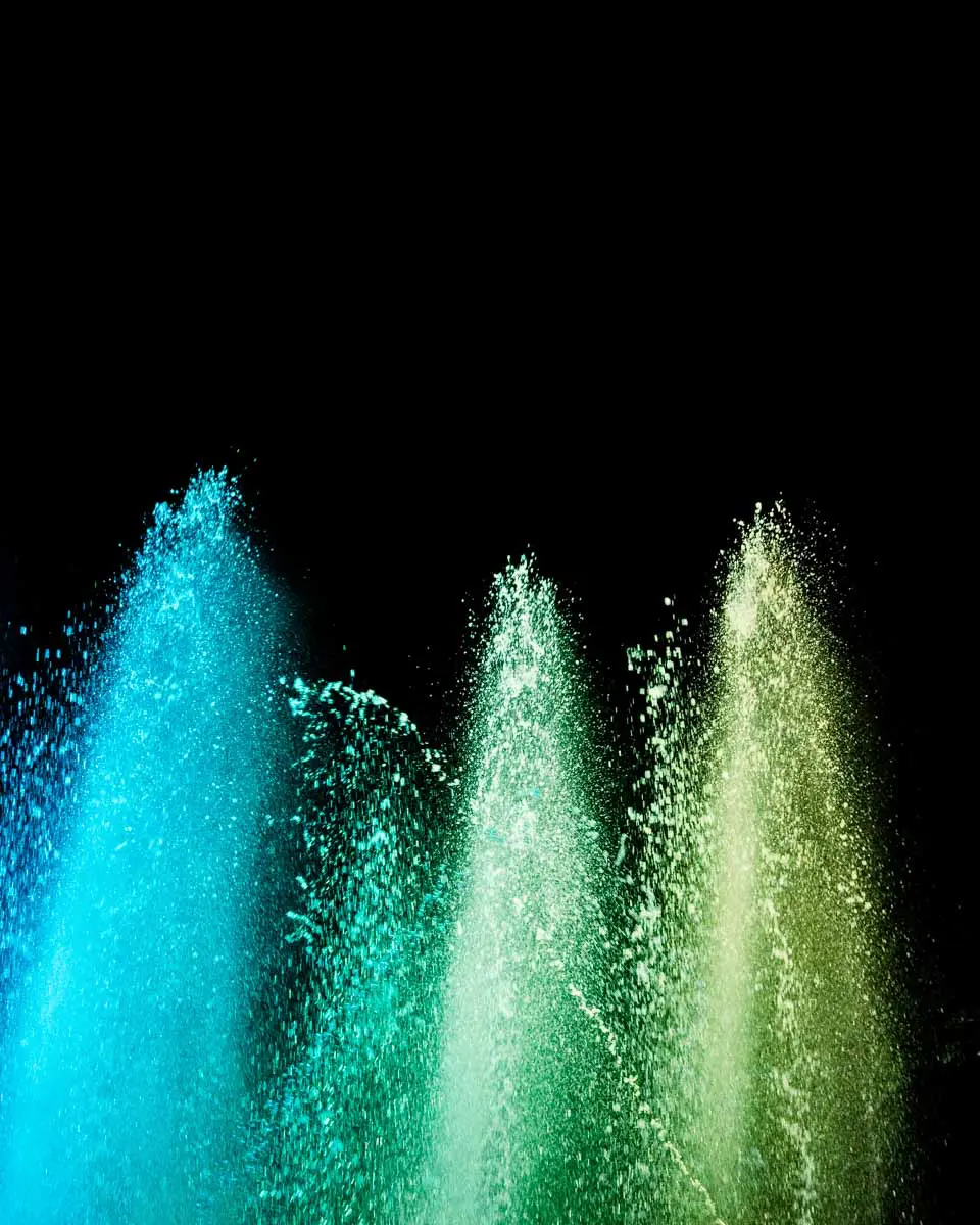 Water jets lit turquoise and green in the night