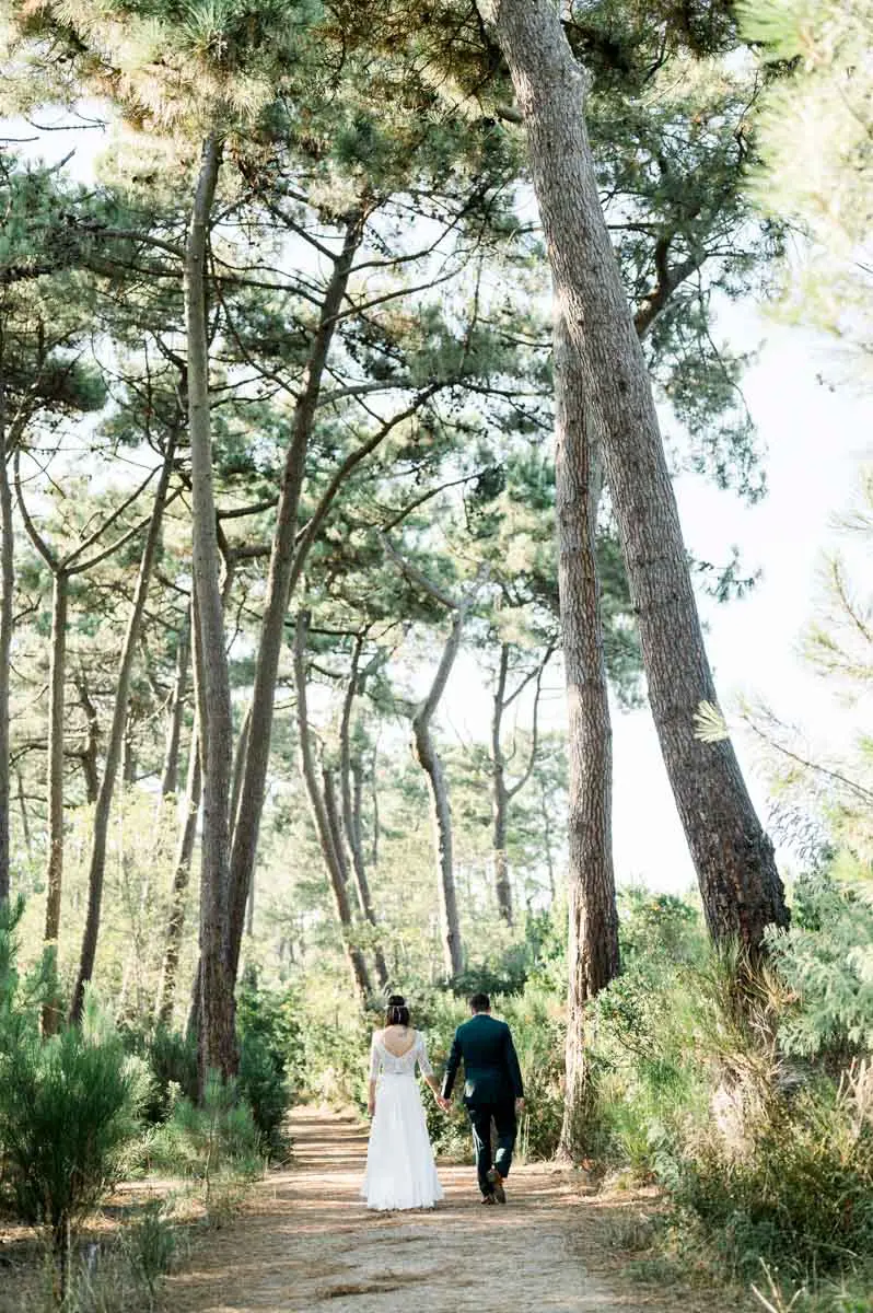 The newlyweds walking along a path lined with tall pines