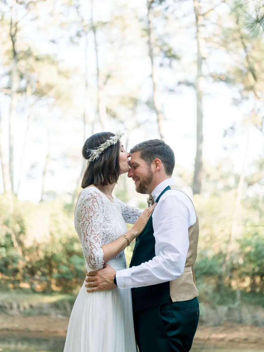 Anne-Sophie and Pierre kissing beneath the pines during their post-wedding shoot