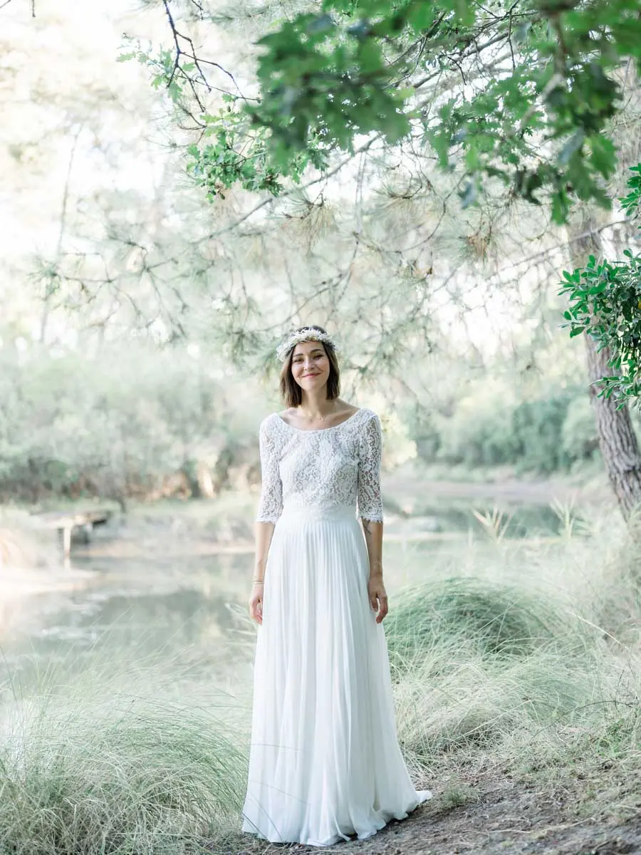 The bride in a flower crown standing among tall grasses