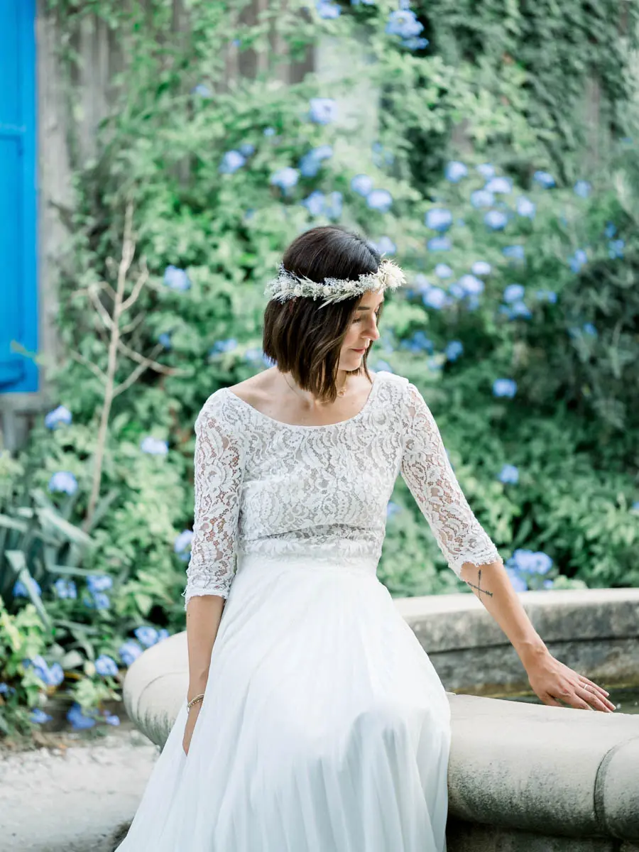 The bride seated beside a blue-flowering plumbago bush
