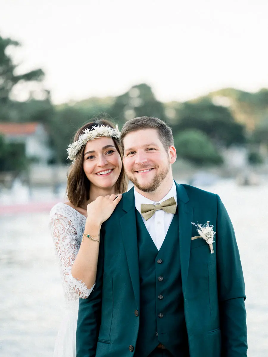 The smiling newlyweds posing by the bay at the end of the day