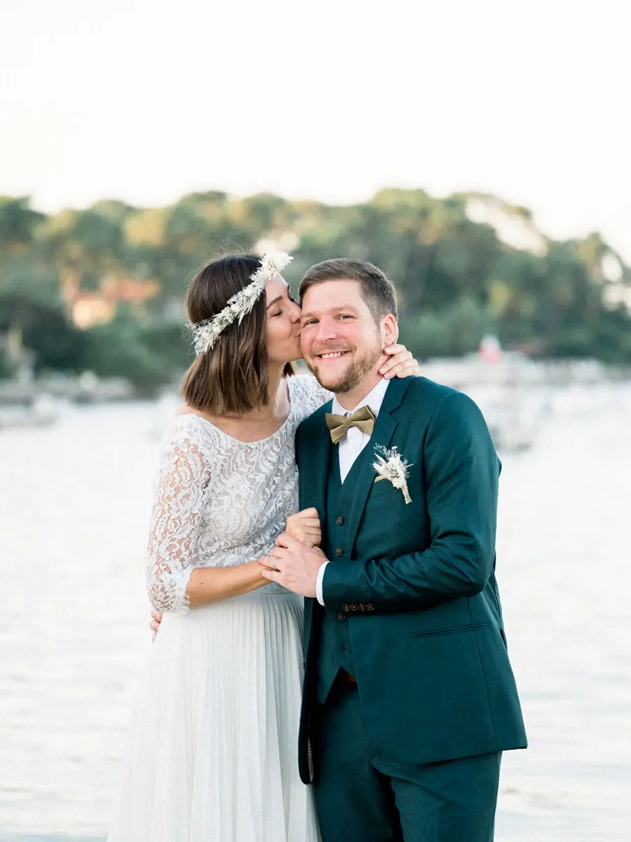 The bride kissing the groom's cheek by Arcachon Bay