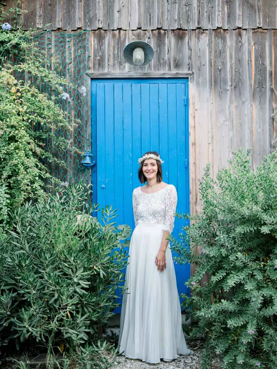 The bride standing before a bright blue door in a wooden hut