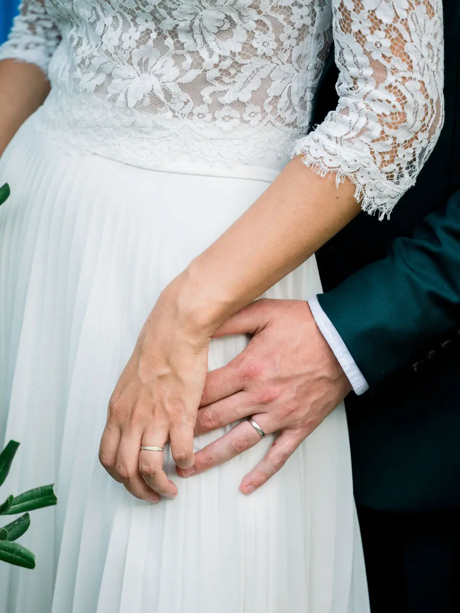 The newlyweds' hands intertwined on the pleated lace gown