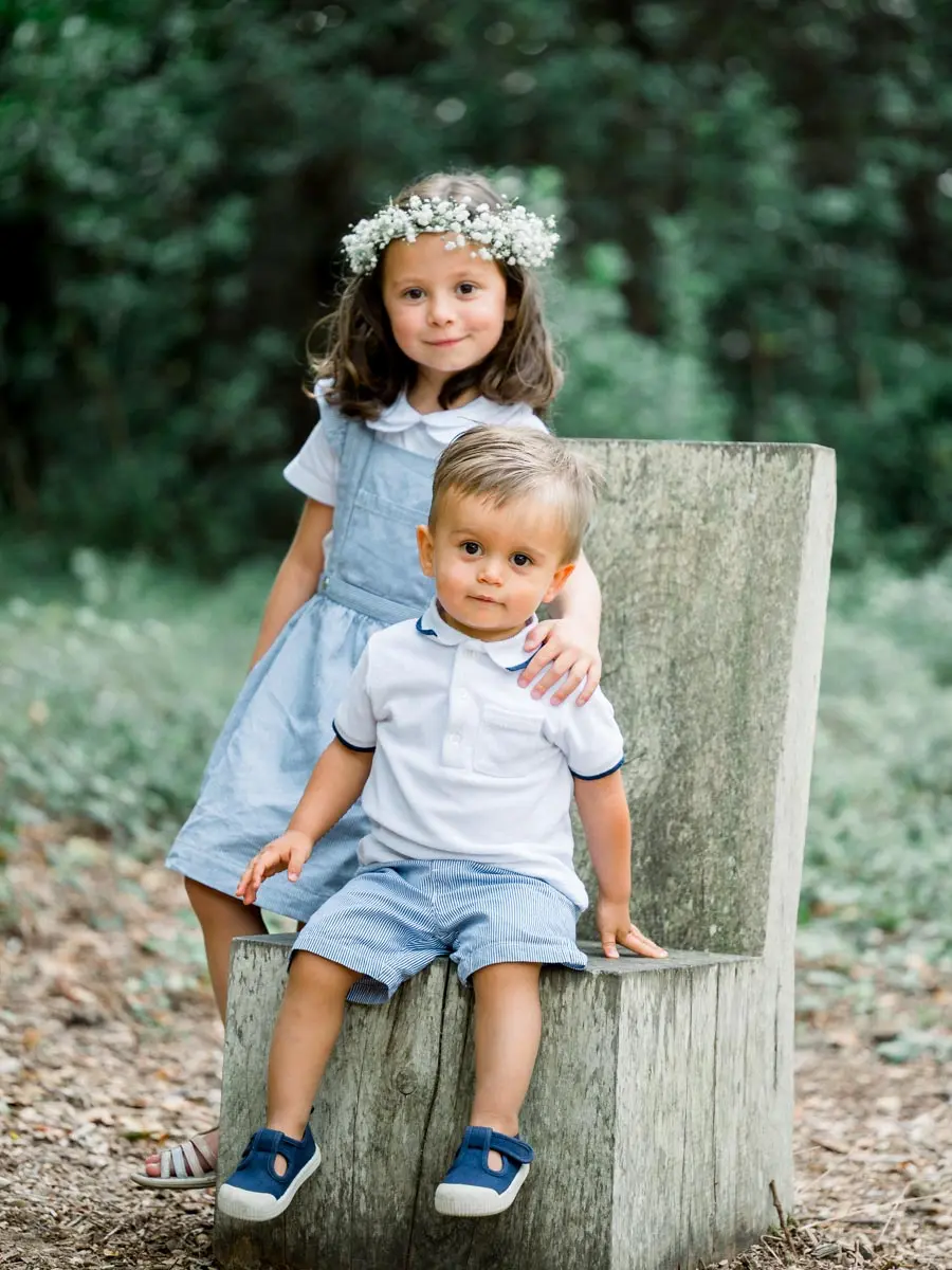 Girl in a flower crown with her little brother on a wooden seat