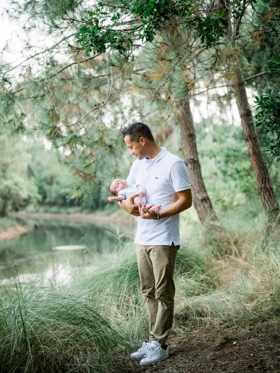 Father cradling his newborn by the water at the Piraillan reservoirs
