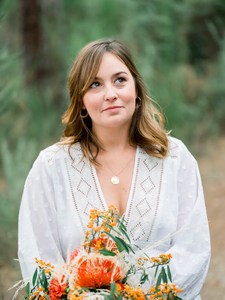 Portrait of the mum-to-be in an embroidered white dress holding an orange bouquet