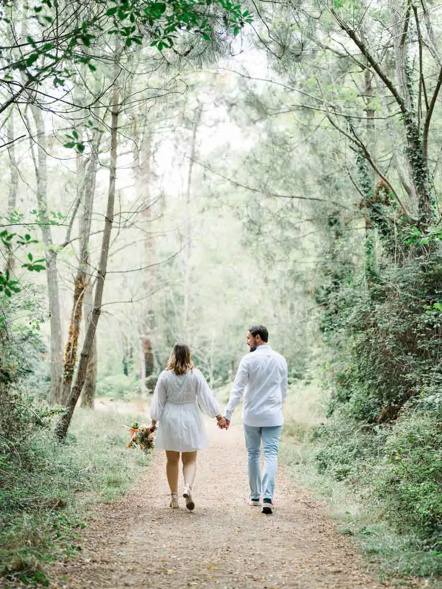 The couple walk hand in hand along a forest track on Arcachon Bay
