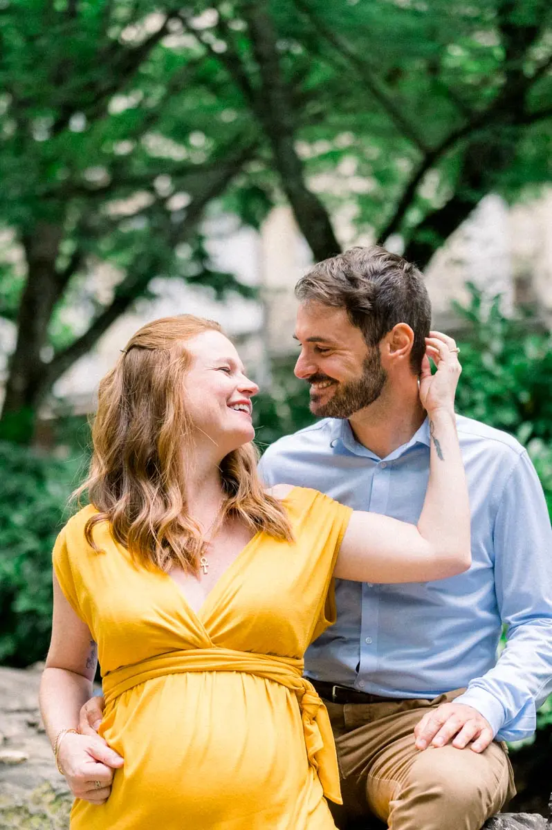 Mum-to-be in a yellow dress sitting with her partner, both smiling