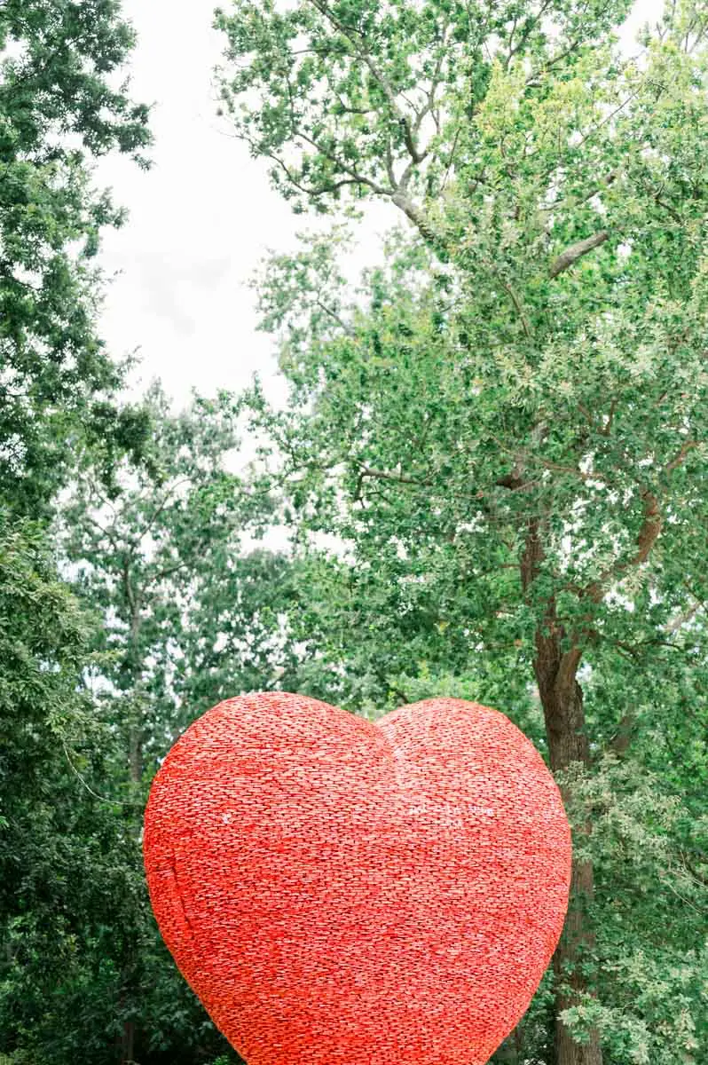 Red heart-shaped sculpture among the trees of the park