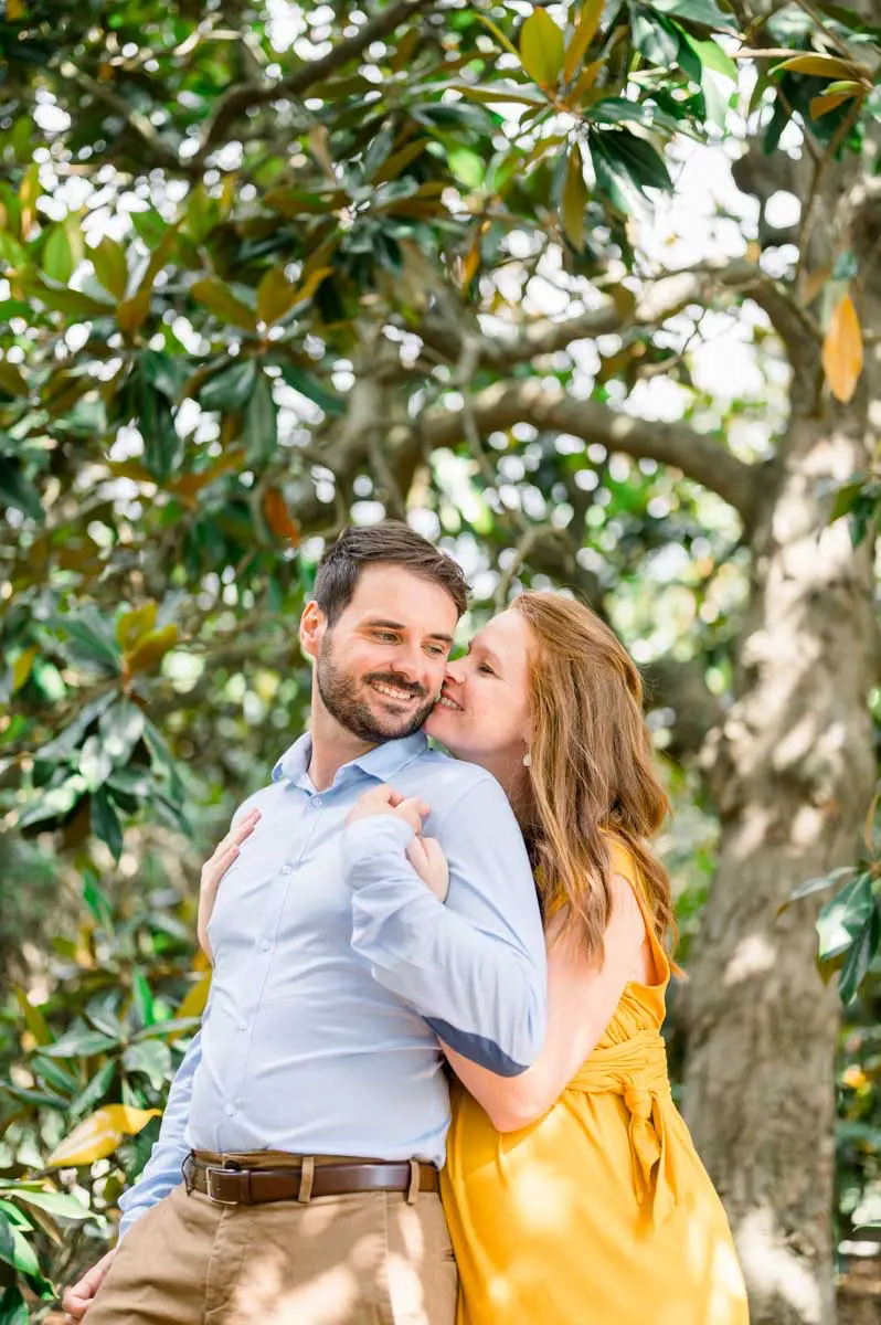 The mum-to-be kisses her partner's cheek under the magnolia