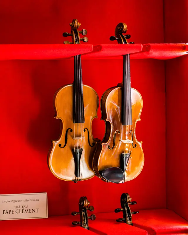 Two antique violins hanging in a red alcove at the château