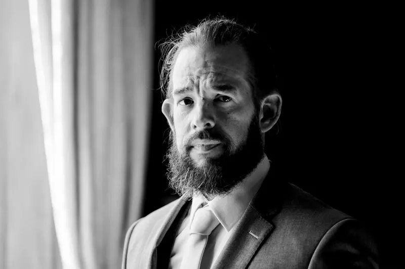Chiaroscuro portrait of the bearded groom getting ready, in black and white
