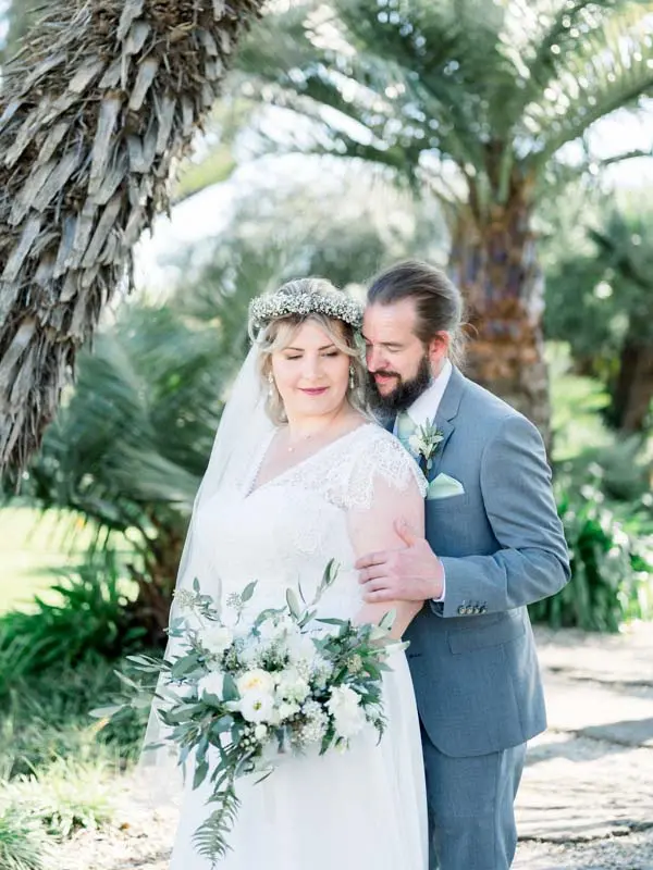 Julie and Derek embracing among the palms at Château Pape Clément