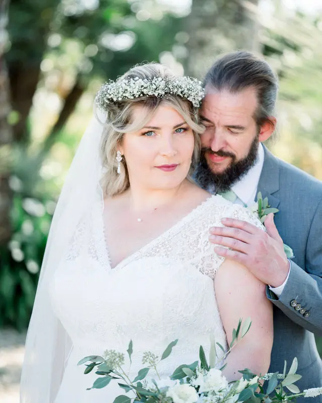 The groom tenderly embracing the bride in her gypsophila crown