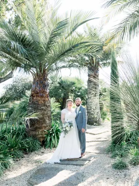 The couple at the end of a palm-lined path in the château grounds
