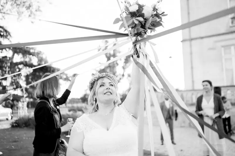 The bride holding the bouquet during the ribbon game among guests, in black and white