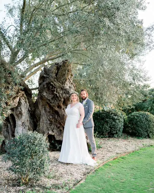 The couple before the gnarled trunk of an ancient olive tree in the grounds
