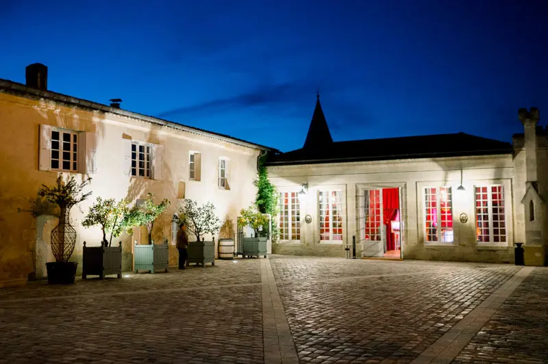 Cobbled courtyard and orangery lit up at nightfall at Château Pape Clément