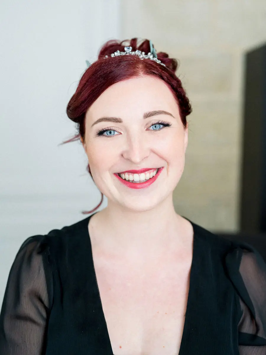 Portrait of the smiling red-haired bride wearing a tiara, make-up by Julia Marty