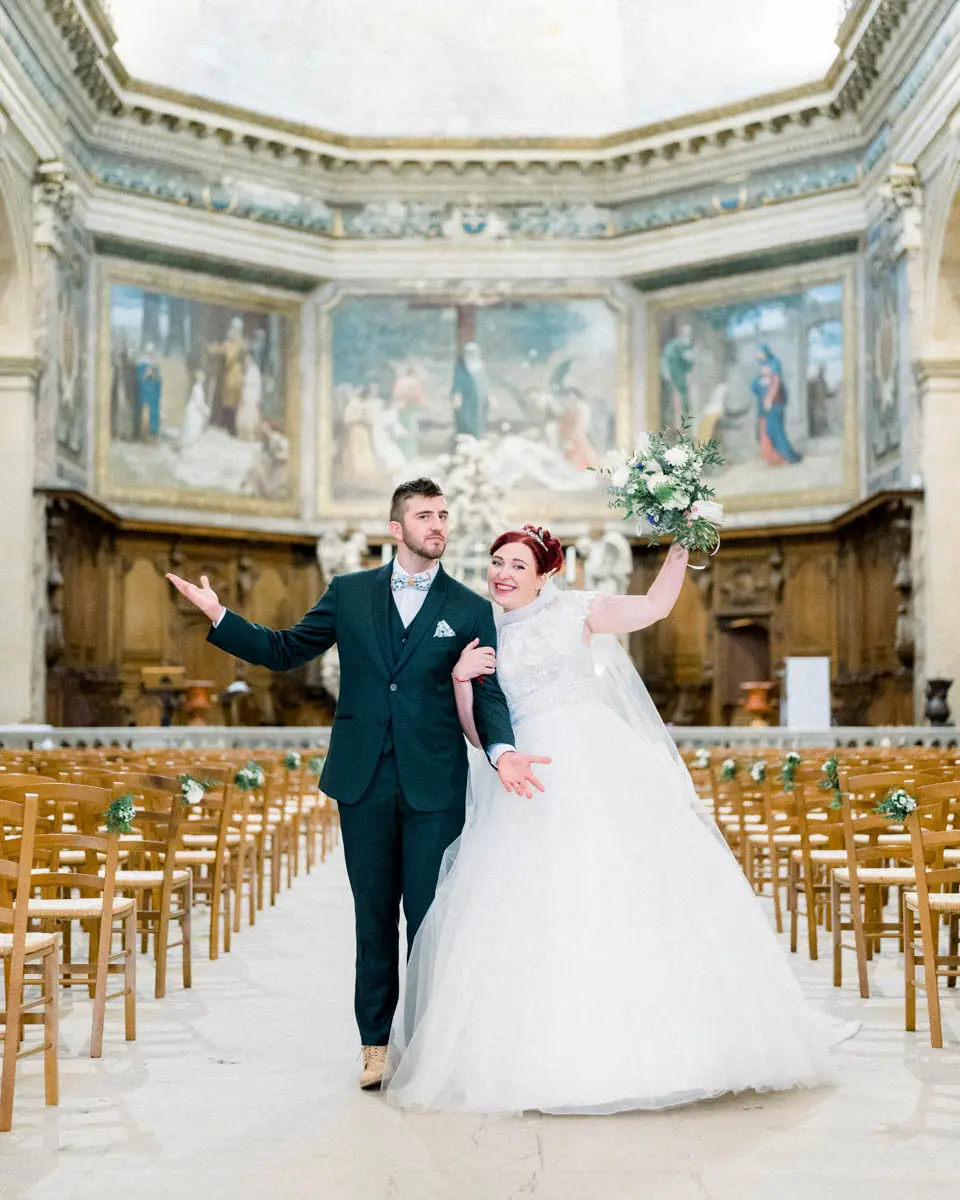 The couple walking back up the church aisle, the groom raising his arm in joy
