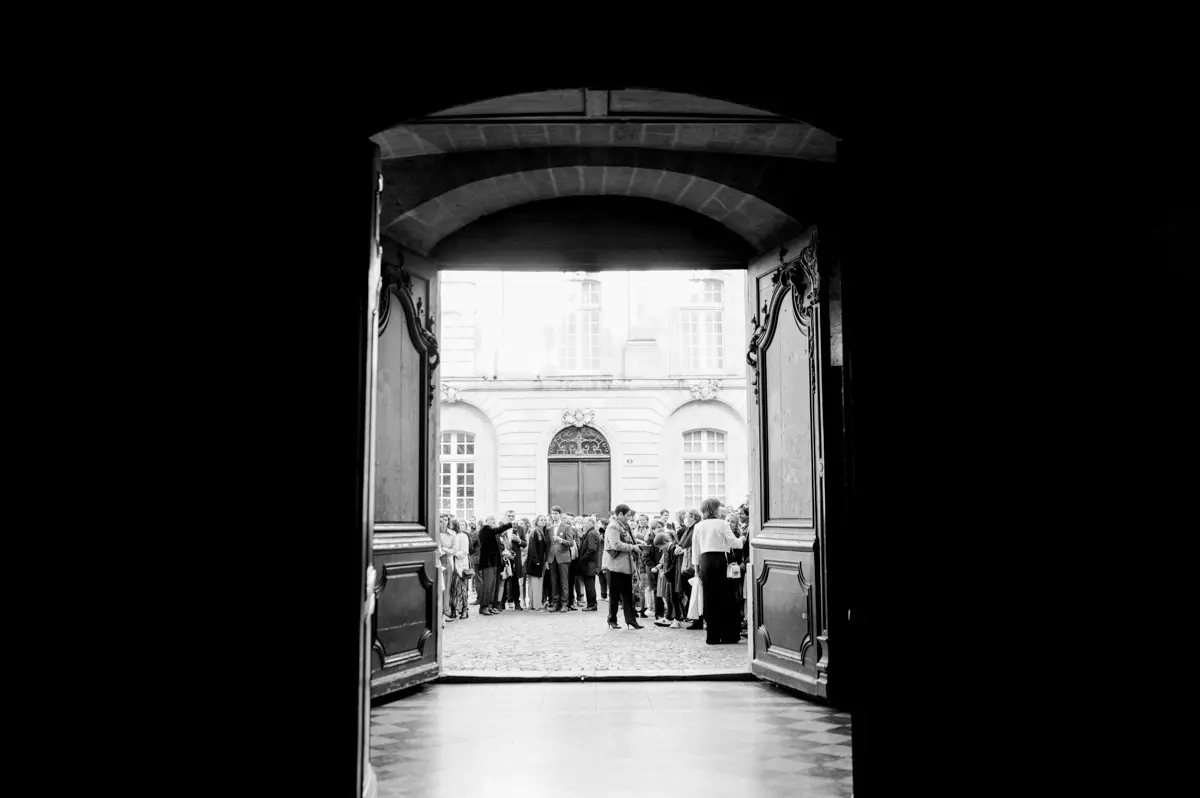 Guests seen from the shadow of the church doorway, in black and white
