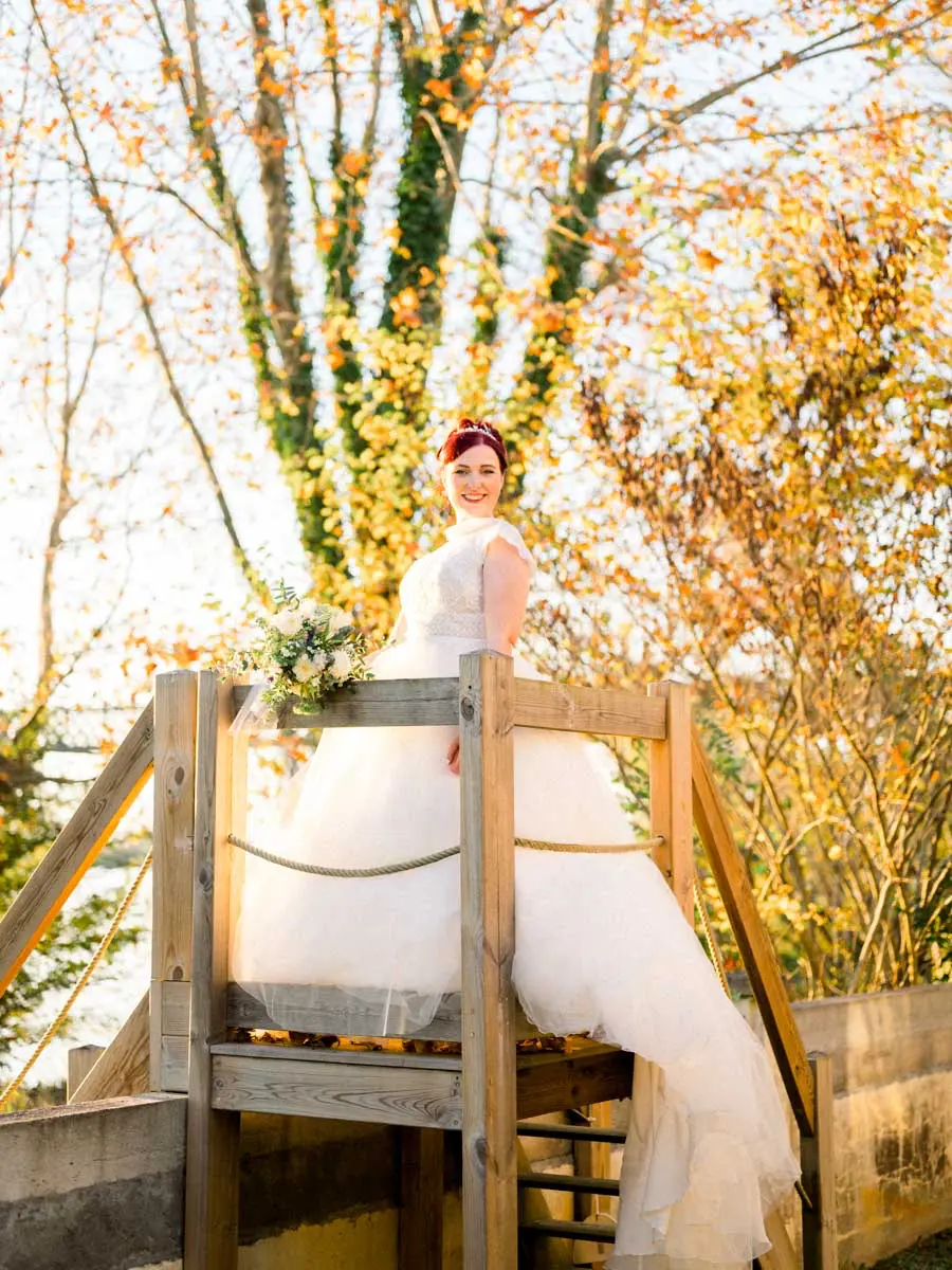 The bride on a wooden platform among autumn trees