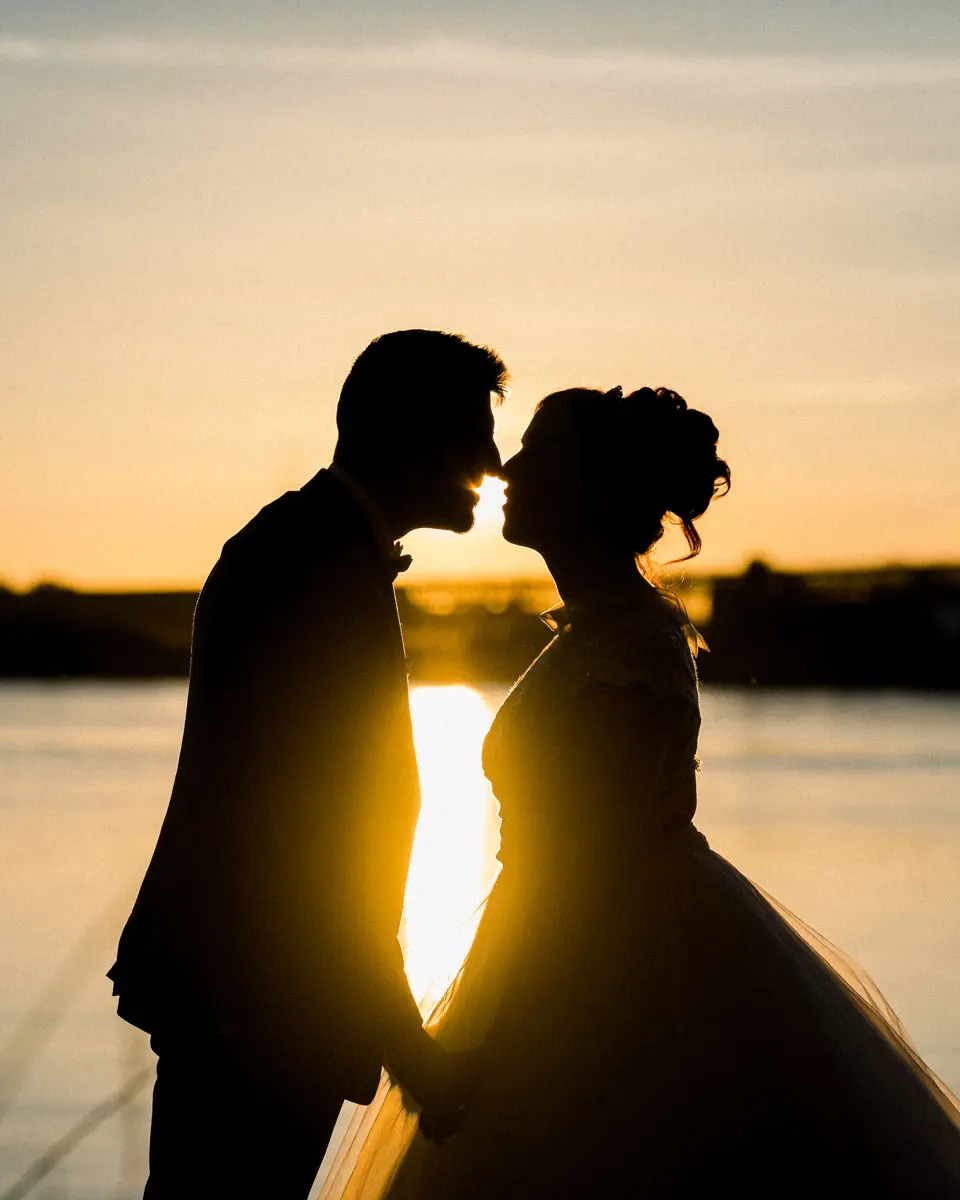 Silhouettes of the couple kissing against the setting sun