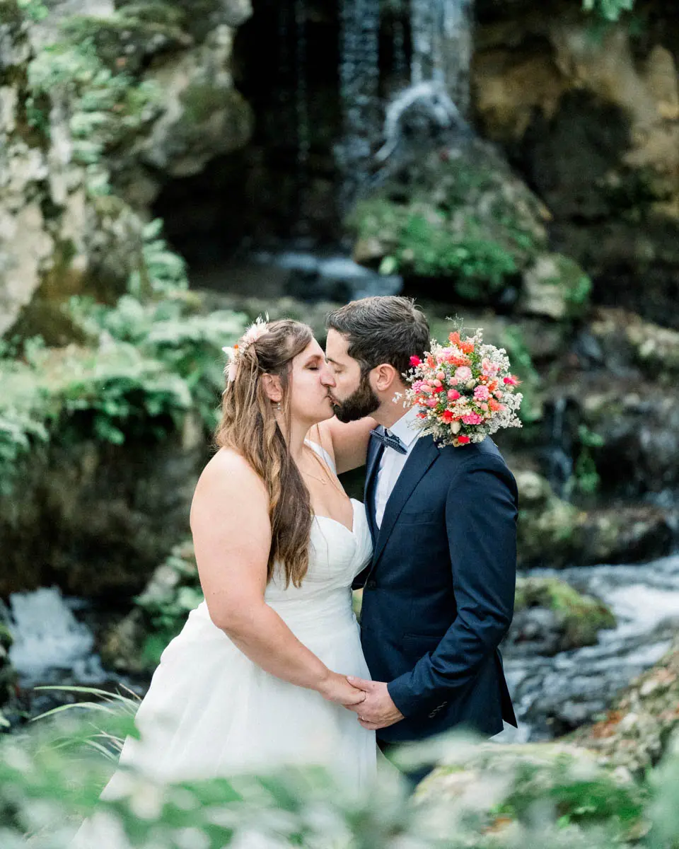 Bride and groom kissing in front of the waterfall in Parc Majolan