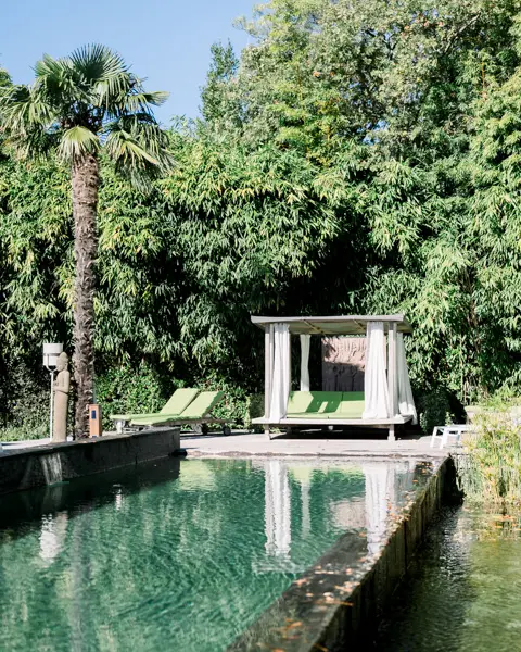 Infinity pool and white pergola surrounded by palm trees at Villa La Tosca