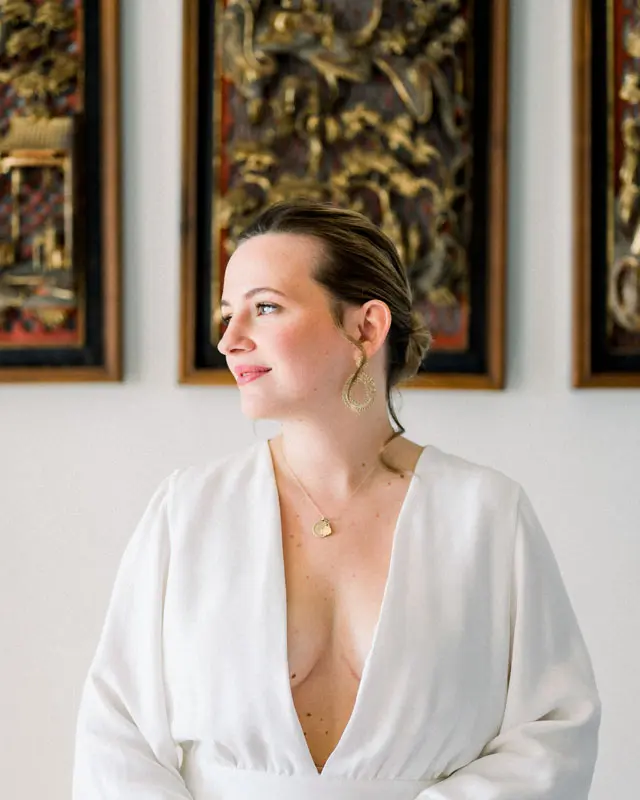 Bride in a plunging white dress in front of carved gilded panels