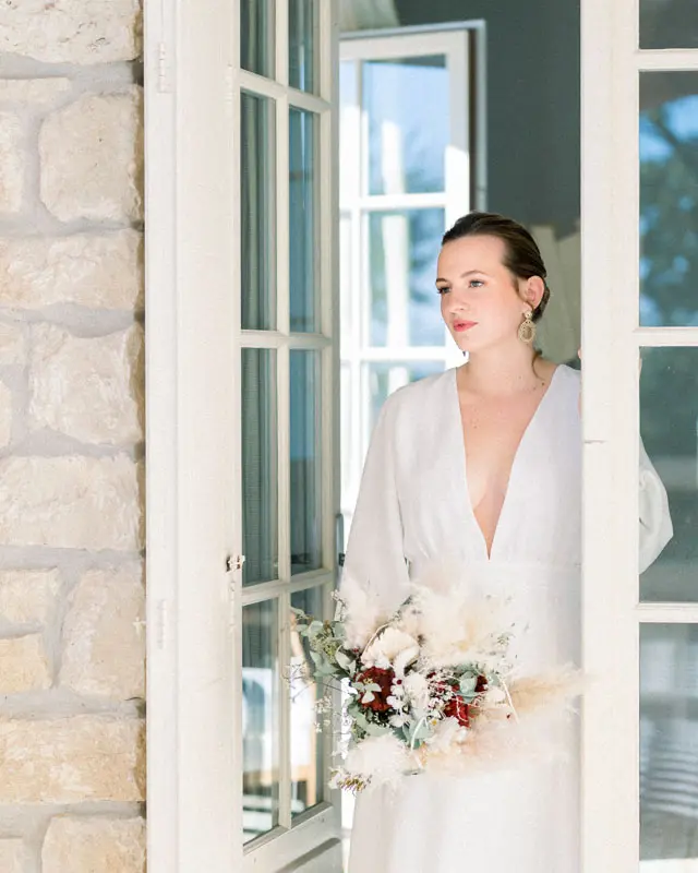 Bride holding her dried flower bouquet in a French window frame