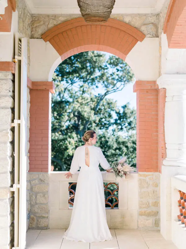 Bride seen from behind under the brick arches of the villa's loggia