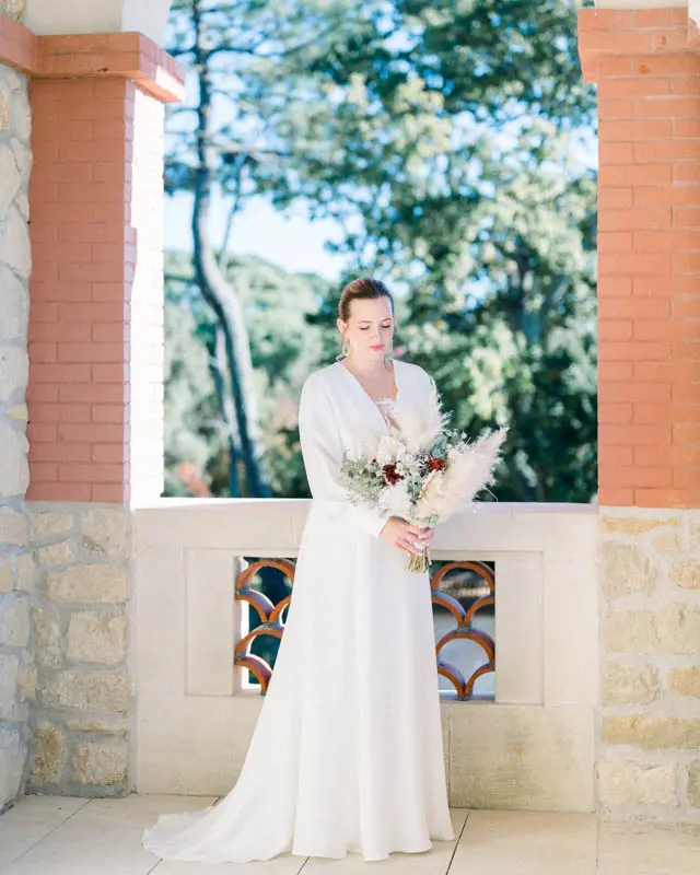 Bride posing on the Villa La Tosca loggia between two brick pillars