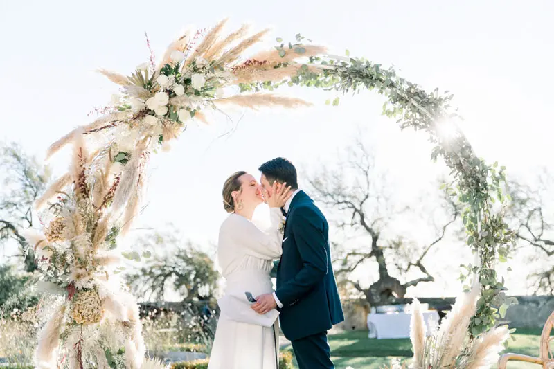Bride and groom kissing under the dried flower arch at the end of the ceremony
