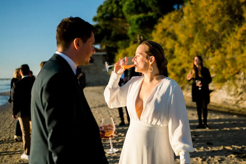Bride and groom sipping drinks on the beach during the cocktail hour