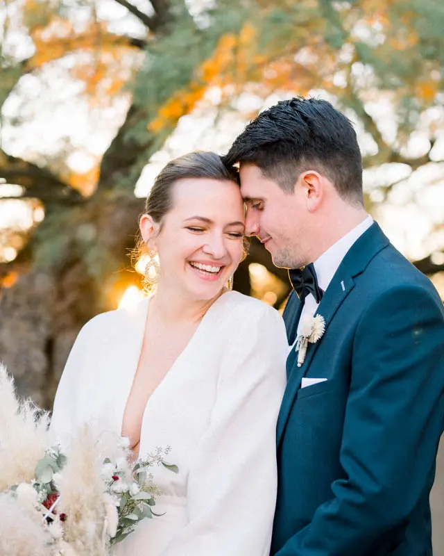 Laughing bride resting her forehead against the groom's in the sunset glow
