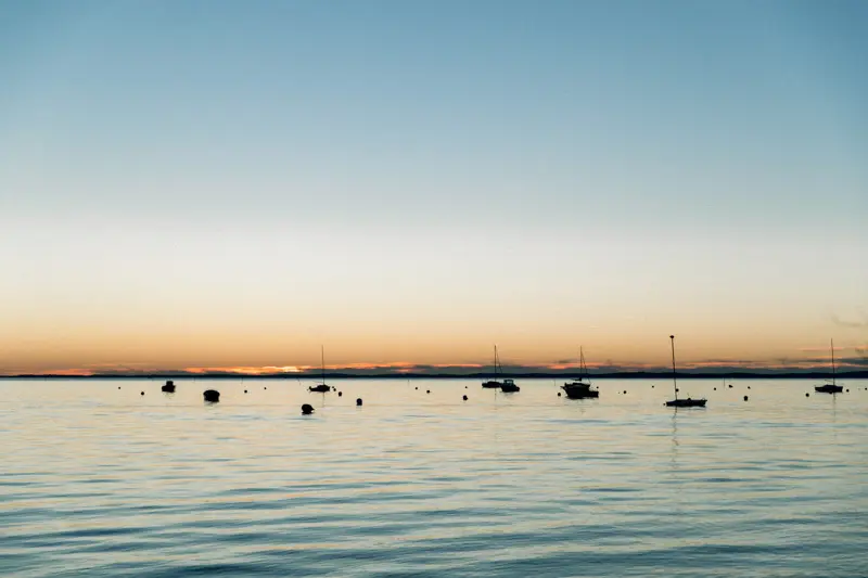 Orange sunset over Arcachon Bay with boats at anchor